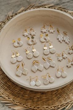 a basket filled with lots of white and gold earring sets on top of a wooden table