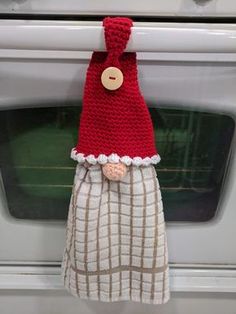 a red knitted hat hanging from the side of an oven door knob on a towel holder