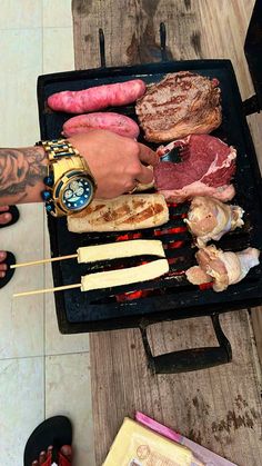 a person is grilling meat and sausages on a bbq with tongs