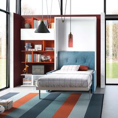 a bedroom with a bed, bookshelf and colorful rugs on the floor