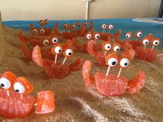 there are many orange crabs with googly eyes on sticks in the sand at the beach