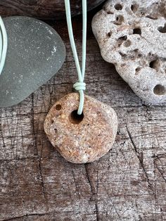 a rock with a cord attached to it sitting on a wooden table next to some rocks