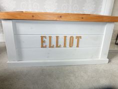 a wooden sign that reads elliot on it's side in front of a wall