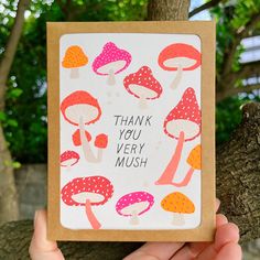 a hand holding up a thank you very mushroom card