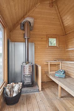 the inside of a wooden cabin with a stove and two benches in front of it