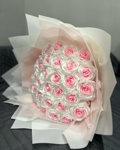 a bouquet of pink and white roses on top of a bed