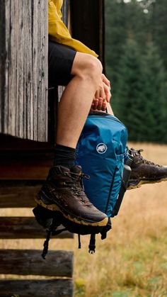 a person sitting on the side of a building with their feet in a blue backpack