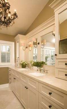 a bathroom with double sinks and two mirrors on the wall above them is decorated in white