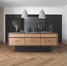 a kitchen with wooden floors and black walls, two pendant lights above the counter top