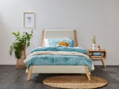 a bed with blue and white comforter in a bedroom next to a wooden table