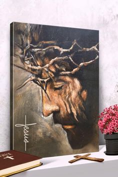 a painting of jesus's face on a shelf next to a book and flowers