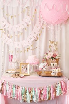 a pink and gold birthday party with bunting, cake and desserts on the table