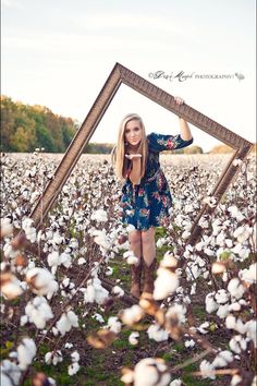 a woman standing in a cotton field holding up a frame