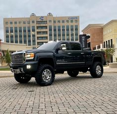 a black truck parked in front of a tall building on a cobblestone street