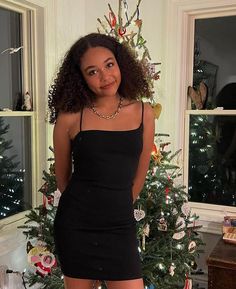 a woman standing in front of a christmas tree