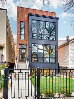 an apartment building with black iron fence and green grass