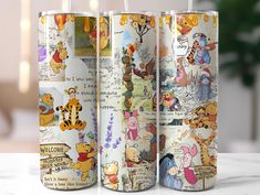 three winnie the pooh travel mugs on a table with disney characters all over them