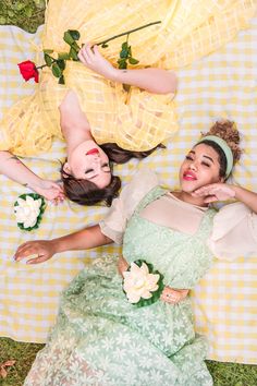 three women in dresses laying on a yellow and white checkered tablecloth with flowers