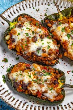 three stuffed peppers on a plate with cheese and seasoning sprinkled around them