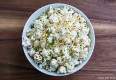 a white bowl filled with popcorn on top of a wooden table