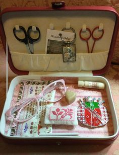 an open suitcase filled with crafting supplies and sewing scissors on top of a table