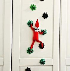 an elf is hanging on the front door with christmas decorations around it's legs