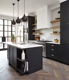 a kitchen with black cabinets and an island in front of the stove, sink and oven