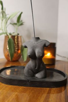 a small gray statue sitting on top of a wooden table next to a potted plant