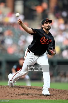 a baseball player throwing a ball on top of a field in front of a crowd