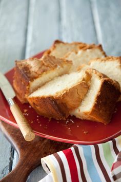 sliced loaf of bread sitting on top of a red plate next to a knife and fork