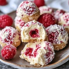 raspberry filled donuts on a plate with powdered sugar and fresh raspberries