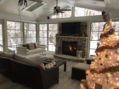 a living room with a christmas tree in the corner and windows to the side that have lights on them