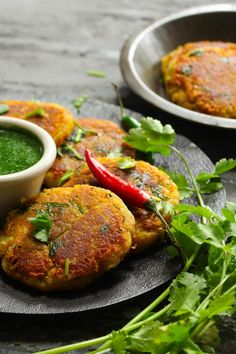 some food is sitting on a plate next to a bowl of green sauce and cilantro