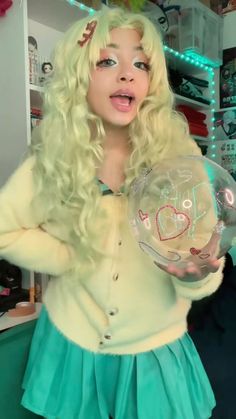 a woman with long blonde hair holding a crystal ball in front of her face and making a funny face