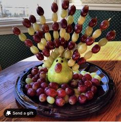 a bowl filled with grapes and fruit on top of a wooden table