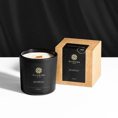 a black candle sitting next to a box on a table with a white surface in front of it