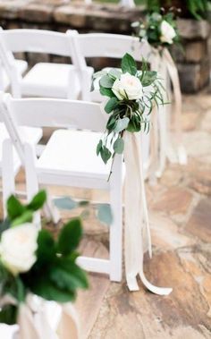 white chairs with flowers and greenery tied to the back are lined up for an outdoor ceremony