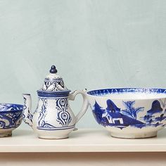 three blue and white bowls sitting on top of a shelf