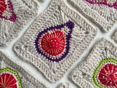 crocheted squares with red, green and purple designs are arranged on a white surface