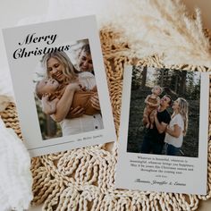 two christmas cards sitting on top of a blanket next to a pile of blankets and pillows