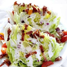 two lettuce salads with bacon and tomatoes on a white plate, ready to be eaten