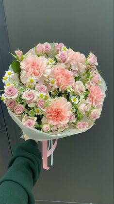 a bouquet of pink and white flowers is being held up by someone's hand