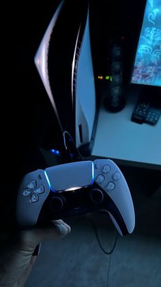 a person holding a video game controller in front of a computer desk with a monitor