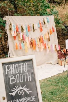 a photo booth with tassels hanging from it's walls and a chalkboard sign in the foreground