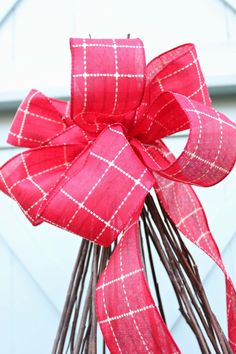 a close up of a red bow hanging from a door with some brown twigs in front of it