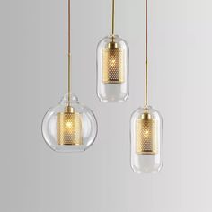 three clear glass pendants with gold accents hanging from a metal rod on a gray background