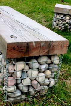 a wooden bench sitting on top of a grass covered field next to a pile of rocks