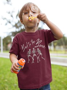 Get ready for Halloween with our "Bad to the Bone" kids' t-shirt! Featuring a fun skeleton graphic and a playful slogan, this shirt is perfect for little ghouls and goblins who love to stand out. Made for both boys and girls, it comes in a range of colors and sizes to fit every trick-or-treater. Check out our size chart to ensure the perfect fit. Plus, we offer easy returns if you need them. Make Halloween extra special with this cool, comfortable tee! The fabric is 100% cotton for solid colors. Halloween Fun Skull Print T-shirt, Kid's Fashion, Toddler Girl Outfit, Halloween All Over Print Short Sleeve T-shirt, Spooky Cotton T-shirt With Skull Print, Bad To The Bone, Toddler Boy Fashion, Halloween Novelty Cotton T-shirt, Trick Or Treater