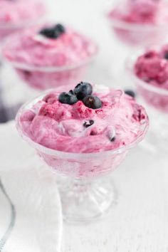 blueberry fool in a glass bowl on a white table with other desserts behind it