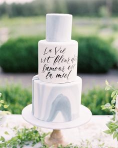 a three tiered wedding cake with handwritten words on the top and bottom layer